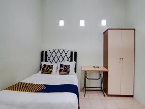 ein Schlafzimmer mit einem Bett und einem kleinen Tisch in der Unterkunft SPOT ON 92797 Awi Stay Syariah in Dumai