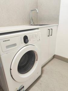 eine Waschmaschine mit einem Waschbecken darüber in der Unterkunft Brand new settled house near shops with Netflix in Weetangerra