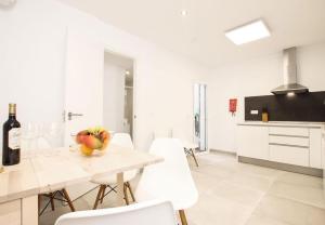 eine weiße Küche mit einem Tisch und weißen Stühlen in der Unterkunft Charming Mallorca Apartment 3 Bedrooms Villa Townhouse Alnair in Port de Pollença