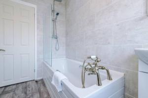 a white bathroom with a tub and a sink at Cosy 3-Bedroom House Near City Centre with Free Parking in York