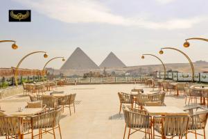 um restaurante com mesas e cadeiras com pirâmides ao fundo em New Comfort Inn Giza no Cairo