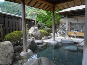 una piscina de agua con rocas en un jardín en Kawakamiya Kasuitei en Gero