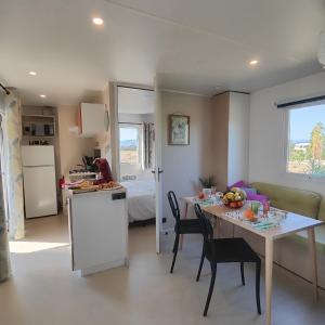 a kitchen and dining room with a table and a room with a bed at Mobil home neuf 4/6 P dans camping 4*- L'Almanarre Hyères - Idéal JO 2024 PACA in Hyères