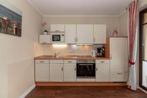 キュールングスボルンにあるUrlaubstraeume-am-Meer-Wohnung-6-8-9808の白いキャビネット、シンク、電子レンジ付きのキッチンが備わります。