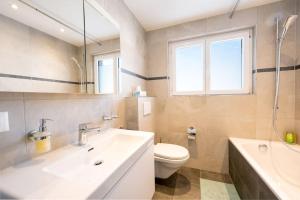 e bagno con lavandino, servizi igienici e vasca. di Idyllic apartment in St. Moritz a Sankt Moritz