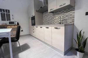 a kitchen with white cabinets and a table with a chair at CasaLina Appartamento in Santa Croce sullʼ Arno