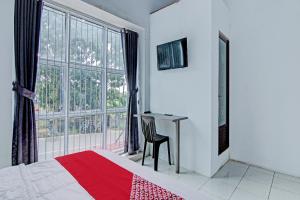- une chambre avec un lit, un bureau et une fenêtre dans l'établissement OYO 92800 Lestari Baru Syariah, à Bangkinang