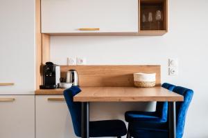 eine kleine Küche mit einem Holztisch und blauen Stühlen in der Unterkunft Dieu Nérée & sa vue mer in Sète