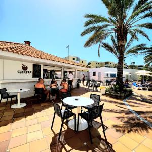 a restaurant with tables and chairs and a palm tree at Luxury Apartment Playa del Inglés in San Bartolomé