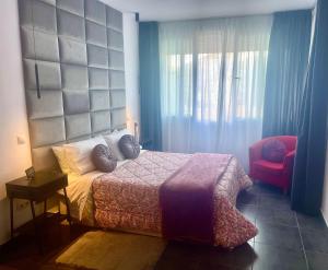 a bedroom with a bed and a red chair at Estudio junto La Nogalera 1 in Torremolinos