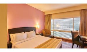 a bedroom with a large bed and a window at FabHotel Prime Centurion in Pune