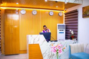 a man sitting at a desk with a laptop at Dozubel Hotel in Abuja