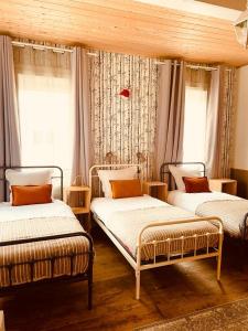 3 lits dans une chambre avec fenêtres et rideaux dans l'établissement Eau Berges, à Vicdessos