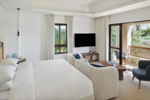 a white bedroom with a large bed and a living room at Elara Villas in Dubai