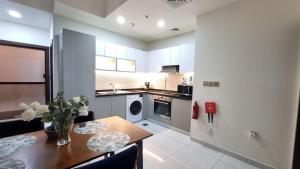 a kitchen with a wooden table and a dining room at Spacious, Economical Apt Near Miralcz Garden in Dubai