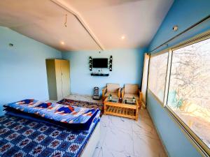 een slaapkamer met een bed, een stoel en een raam bij The Pahadi Nest Mukteshwar in Mukteswar