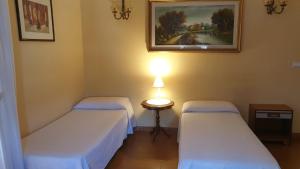 um quarto com duas camas e uma mesa com um candeeiro em Casa vacanze Ada em Capo dʼOrlando