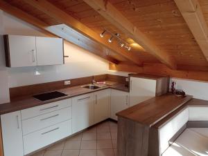 Il comprend une cuisine avec des placards blancs et un plafond en bois. dans l'établissement Ferienwohnungen Zeppenhof, à Santa Valburga
