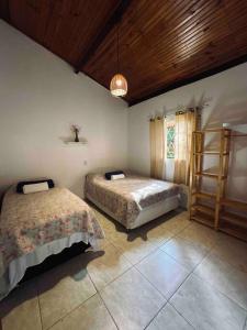 a bedroom with two beds and a wooden ceiling at Casa Amarela - Aconchegante e Familiar in Alto Paraíso de Goiás