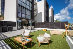 辛普森灣的住宿－The Hills Residence，一个带草地和椅子的庭院以及一张桌子