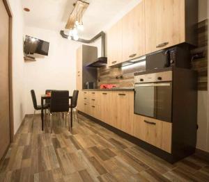 サンタ・クローチェ・スルアーノにあるCasAlfredo Appartamentoのキッチン(木製キャビネット、テーブル、椅子付)