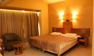 um quarto de hotel com uma cama e uma cadeira em FabHotel Prime Orchard Hospitality em Pune