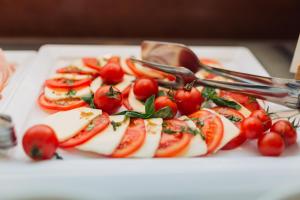 a plate of food with cherries and tomatoes and spoons at DoubleTree by Hilton Hotel Cluj - City Plaza in Cluj-Napoca