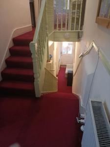 a stairway with a red carpet and a stair case at Alysguesthub in London