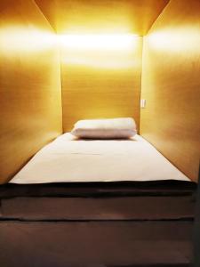 a small bed in a room with wooden walls at Fora Capsule Hostel Tuban Kuta Bali in Kuta
