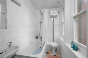 a bathroom with a tub and a toilet and a sink at Brick Lane, London - Lovely One Bedroom Apartment in London