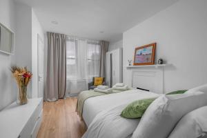 a white bedroom with a large bed and a window at Brick Lane, London - Lovely One Bedroom Apartment in London