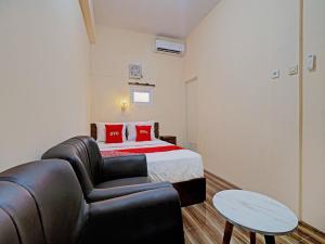 een slaapkamer met een bed, een bank en een stoel bij OYO 92871 Ciparay Residence in Bandung