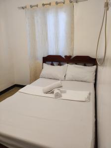 a bed with white sheets and a towel on it at Hidden Gem Siargao in General Luna