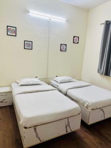 three beds in a room with white walls and wood floors at Elite Stays Viman nagar in Pune