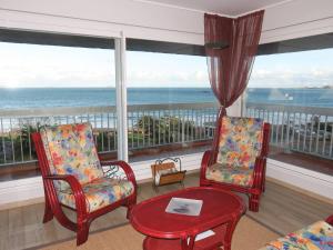 a living room with two chairs and a table and windows at Appartement à Perros-Guirec avec Vue Panoramique, Terrasse et Parking Privé - FR-1-368-271 in Perros-Guirec