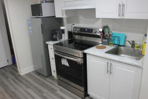 una cocina con fogones negros junto a un fregadero en Comfy basement near KW airport, en Kitchener