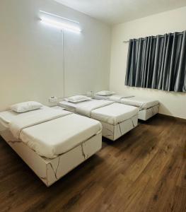 three beds in a room with wooden floors at Elite Stays Viman nagar in Pune +3 photos