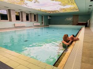 a woman and child sitting in a swimming pool at Hotel Kamzík *** in Malá Morávka