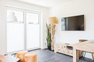 Dünenquartier Apartment 15 في زنغست: غرفة معيشة بيضاء مع طاولة وتلفزيون