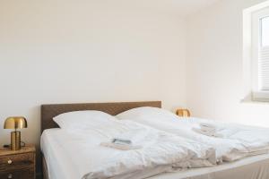 Dünenquartier Apartment 15 في زنغست: سرير ابيض وعليه شراشف ومناشف بيضاء