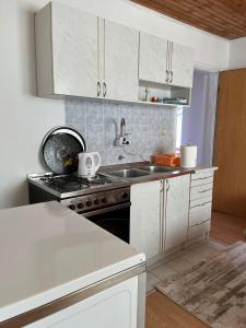 a kitchen with white cabinets and a sink and a stove at Kuca za odmor Marija in Kupres