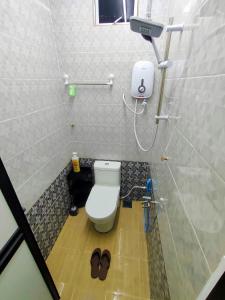 e bagno con servizi igienici e un paio di pantofole. di Raihan Homestay B Kubang Kerian,Free Wifi a Kota Bharu