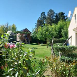 einen Garten mit einem Haus und ein paar Blumen und Bäumen in der Unterkunft Le petit Radieux in Gémozac
