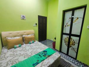 a bedroom with a bed in a room with green walls at Raihan Homestay B Kubang Kerian,Free Wifi in Kota Bharu