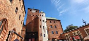 a building with a clock tower next to two brick buildings at Solaris 711, sea view. in Darłowo +6 photos