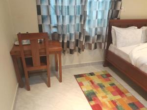 1 dormitorio con escritorio, 1 cama y 1 silla en PALAZZO GARDEN RESORT MATEMA, en Kyela