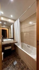 uma casa de banho com uma banheira e um lavatório e uma banheira em By the Sea IV - Cosy flat no Funchal