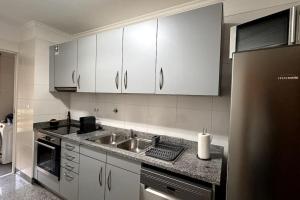 uma cozinha com armários brancos e um lavatório em By the Sea IV - Cosy flat no Funchal