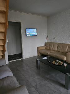 a living room with a couch and a tv on the wall at Vakantiehuis Zuiderveld in Geesbrug