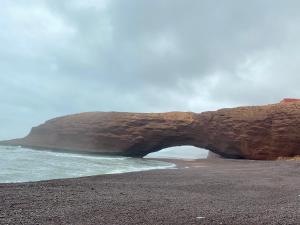 an arch on a rocky beach next to the ocean at Kassbah legzira in Sidi Ifni
